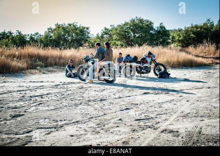 Four motorcycle friends taking a break on arid plain, Cagliari, Sardinia, Italy Stock Photo