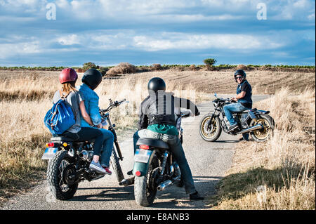 Rear view of four friends chatting on motorcycles on rural road, Cagliari, Sardinia, Italy Stock Photo