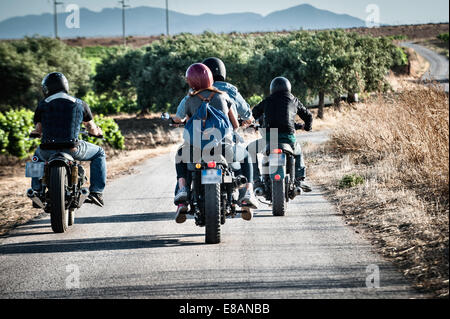 Rear view of four friends motorcycling on rural road, Cagliari, Sardinia, Italy Stock Photo