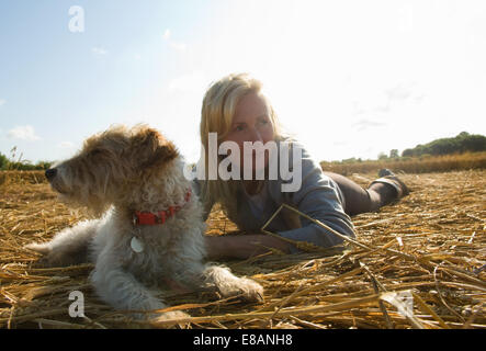 Woman and Jack Russell Terrier lying on field Stock Photo