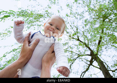 Father holding up baby daughter in garden Stock Photo