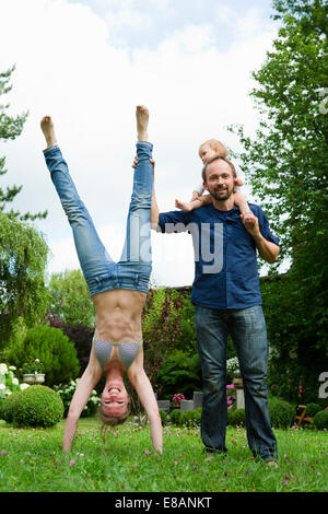 Mother doing handstand in garden next to family Stock Photo