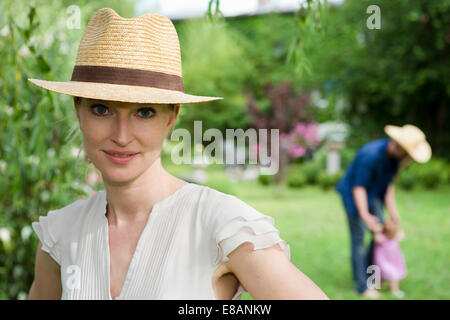 Portrait of mid adult woman in front of family in garden Stock Photo