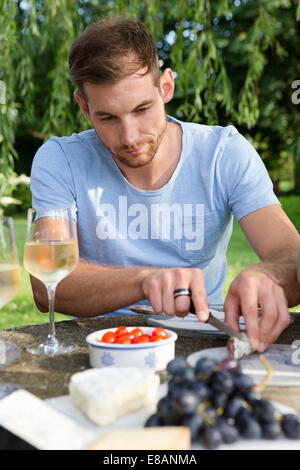 Mid adult man sitting at picnic table in garden