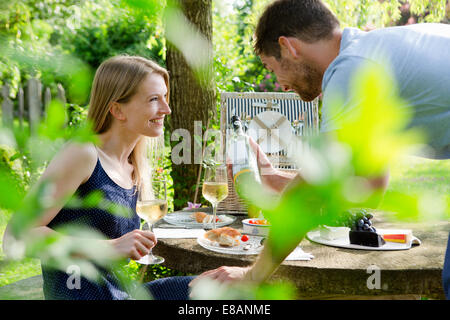 Mid adult couple having picnic with white wine in garden Stock Photo