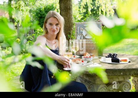 Portrait of mid adult woman sitting at picnic table in garden Stock Photo