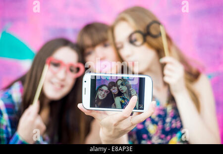 Friends taking selfie wearing fake spectacles and lips Stock Photo