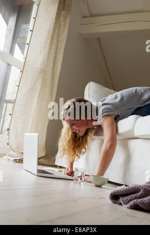 Woman lying on sofa using laptop Stock Photo