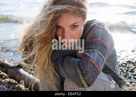 Woman sitting on windy beach Stock Photo
