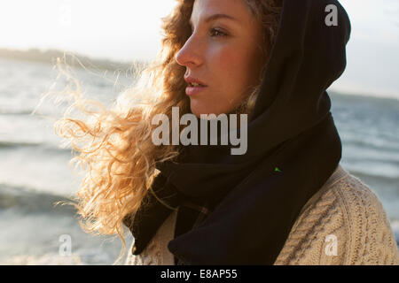 Woman all wrapped up on windy beach Stock Photo