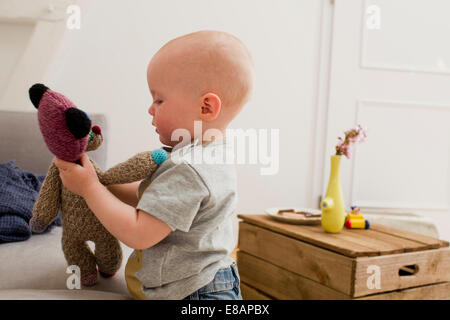 Baby girl pointing playing with teddy bear in sitting room