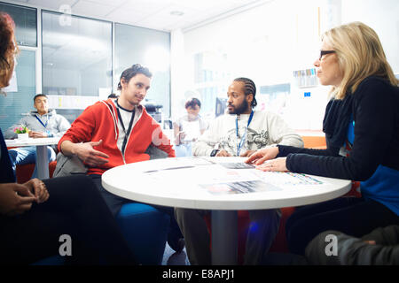 Female lecturer and a group of college students having informal discussion in classroom Stock Photo