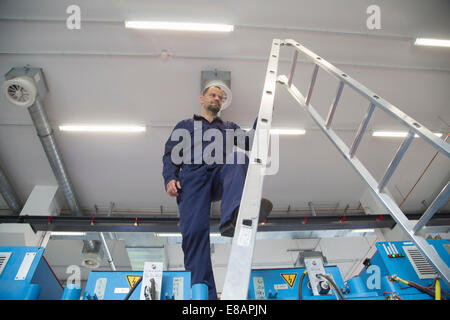 Worker on ladder in industrial plant Stock Photo