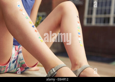 Close up of girls legs with rows of star stickers Stock Photo