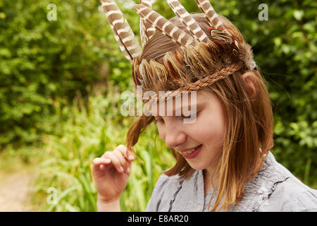 Girl in feather headdress playing with hair Stock Photo