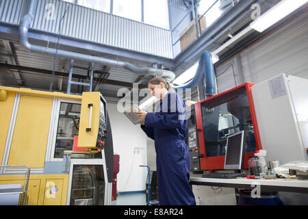 Female engineer monitoring factory machinery using digital tablet Stock Photo