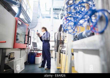 Female engineer monitoring automated machinery using digital tablet Stock Photo