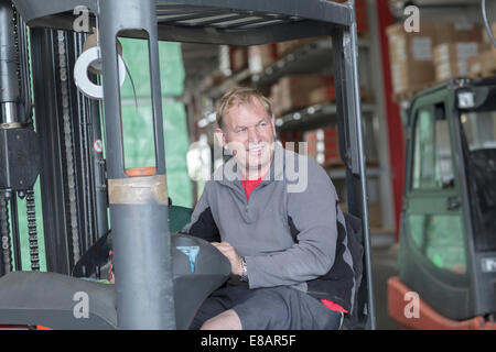 Worker driving forklift truck in hardware store warehouse Stock Photo