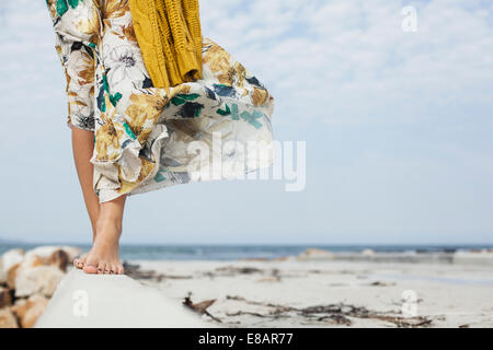 Young womans legs walking along cement block on beach, Cape Town, Western Cape, South Africa