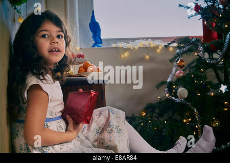 Portrait of girl sitting on floor with christmas present Stock Photo