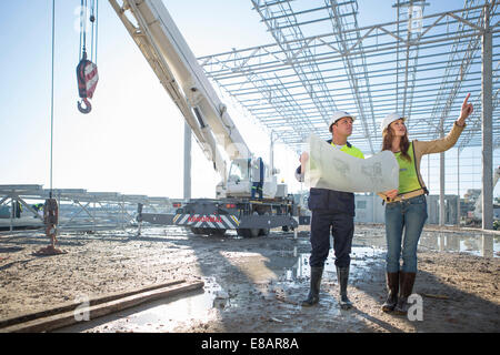 Site manager and architect checking blueprint on construction site Stock Photo