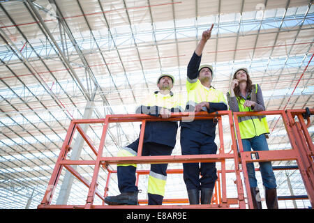 Low angle view of site managers and architect pointing from viewing platform on construction site Stock Photo