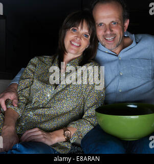 Mature couple watching TV with snack bowl Stock Photo