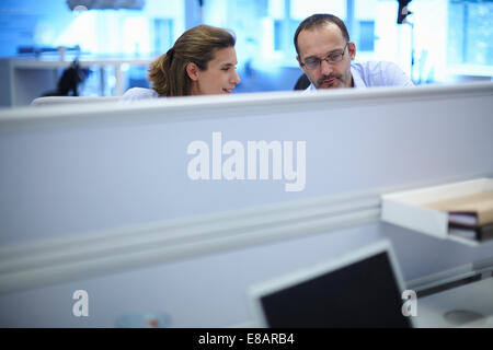 Businessman and businesswoman chatting at their desks in office