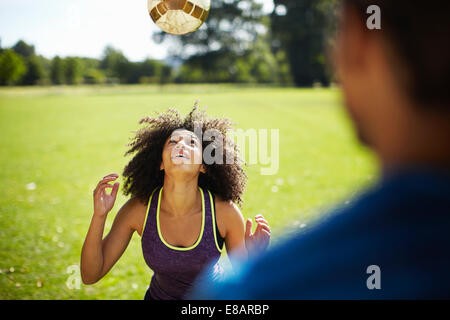 Young woman heading football in park Stock Photo