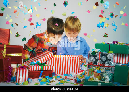 Two brothers open mouthed on unwrapping glowing christmas gift box with exploding confetti Stock Photo