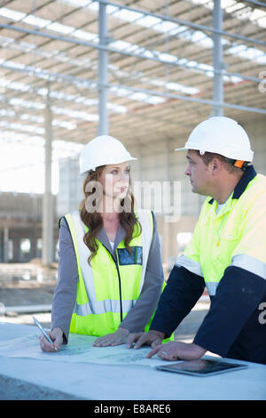 Site manager and architect with digital tablet and blueprint on construction site Stock Photo