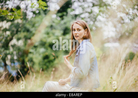 Portrait of young woman with hand in hair in field Stock Photo