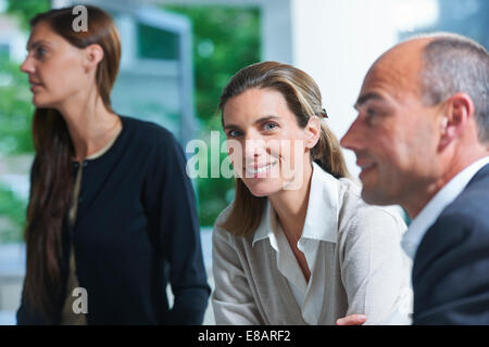 Portrait of businesswoman between colleagues in office Stock Photo