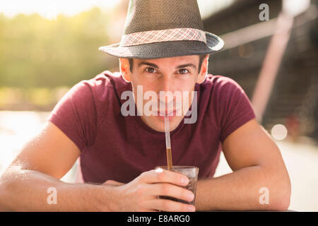 Young man wearing hat drinking through straw Stock Photo