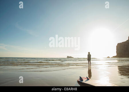 Senior woman surfer standing looking out to sea, Camaret-sur-mer, Brittany, France Stock Photo