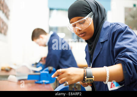 Female student using vice grip in college workshop
