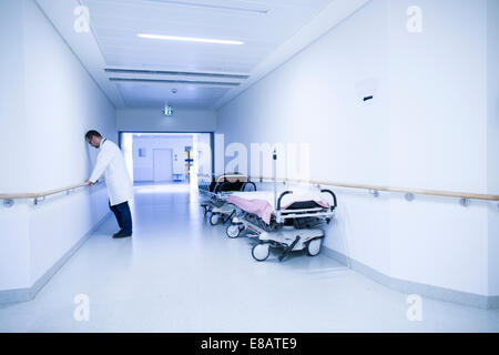 Stressed doctor with head down in hospital corridor Stock Photo