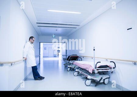 Worried doctor with head down in hospital corridor Stock Photo