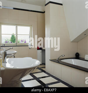 Black+white tiled floor in modern tiled bathroom with black tiled edging on bath Stock Photo