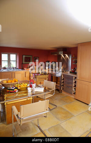 Modern beige leather chairs and glass dining table in red cottage kitchen extension with stone flooring Stock Photo
