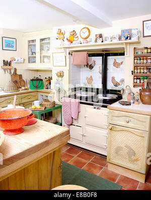 White Aga oven and terracotta tiled floor in cottage kitchen with painted trompe l'oeil rabbit on cupboard door Stock Photo