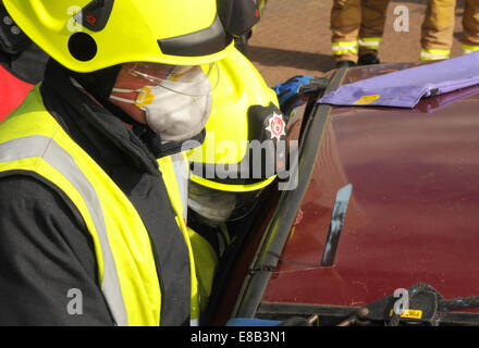 Fire service officer cutting the roof from a crashed car Suitable for emergency service and insurance industry use. Stock Photo