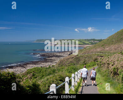Couple walking on section of Wales Coast Path between Mumbles and Langland Bay, looking west Gower Peninsula Swansea Wales UK Stock Photo