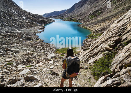 back view of a woman backpacker looking down at glacial lakes in the Darwin Canyon of Kings Canyon National Park Stock Photo