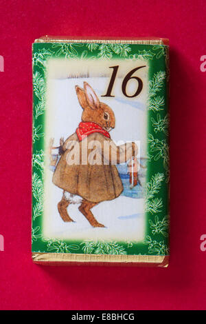 Count down to Christmas with individual advent chocolate bars isolated on red background - calendar day 16 of set of 24 Stock Photo
