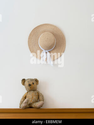 Threadbare One Eyed Teddy bear and a womans straw hat Stock Photo