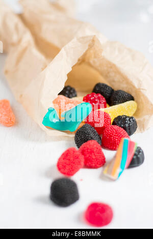 Bag of delicious candy, jelly beans scattered on white table. Vertical image Stock Photo