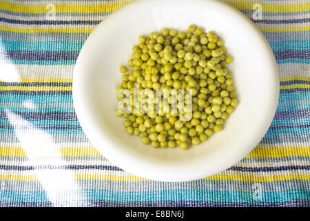 Plate of peas in plate on blue striped background Stock Photo