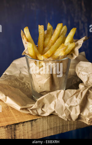 fries, homemade, wrapped in paper, on wood and blue background Stock Photo