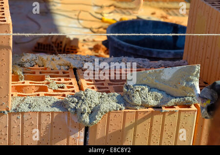 Mason lays the geout with a trowel on blocks of poroton Stock Photo